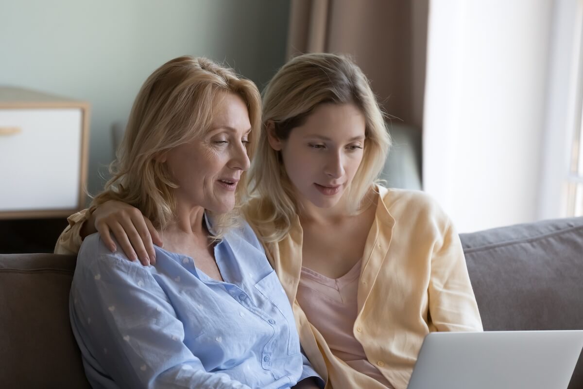 Focused positive mature mother and beautiful young grownup daughter using online ecommerce app on laptop