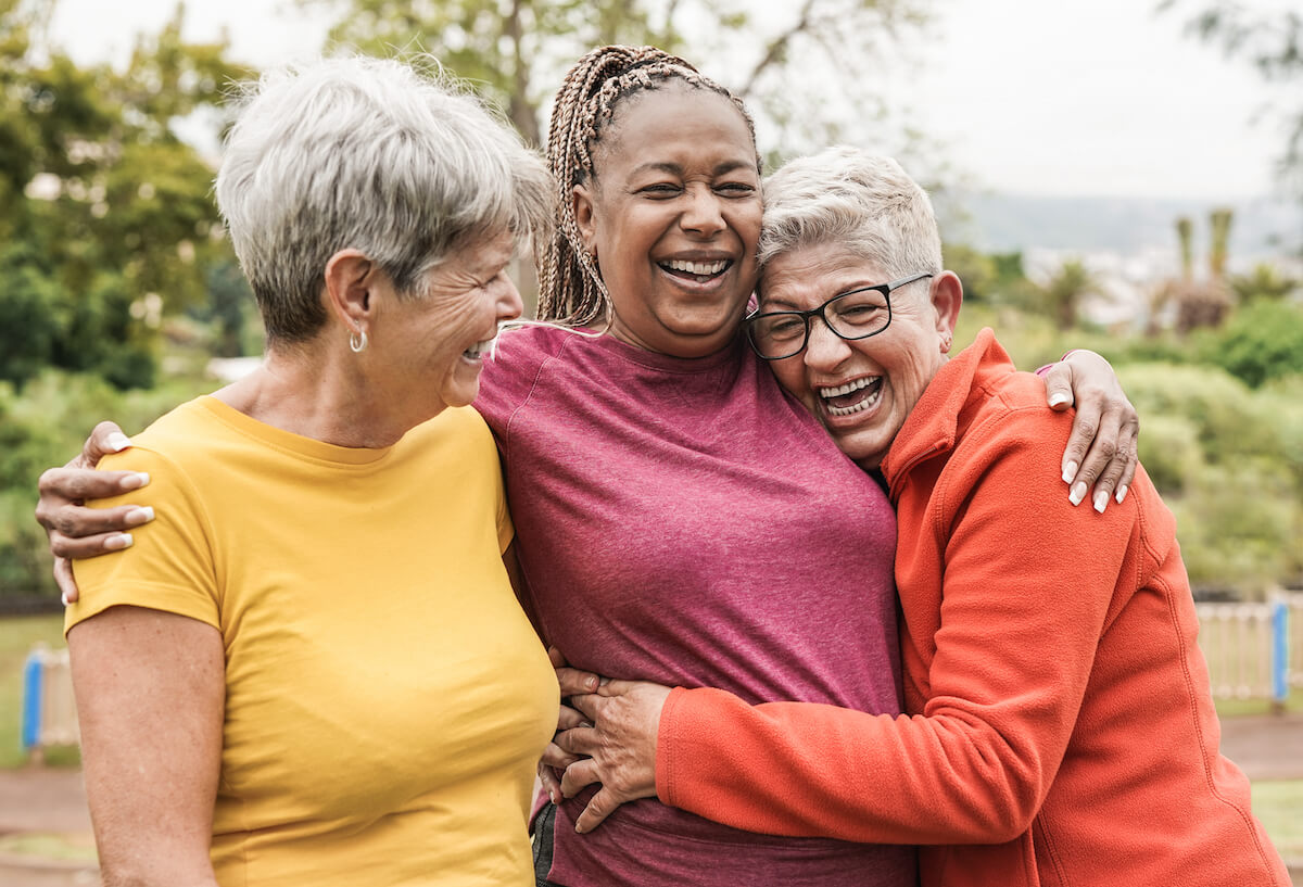Three older women friends hugging and laughing